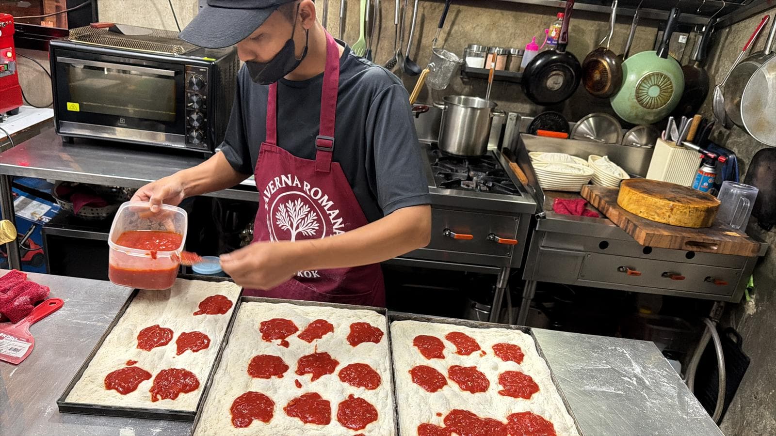 Hands working pizza dough in our Bangkok kitchen